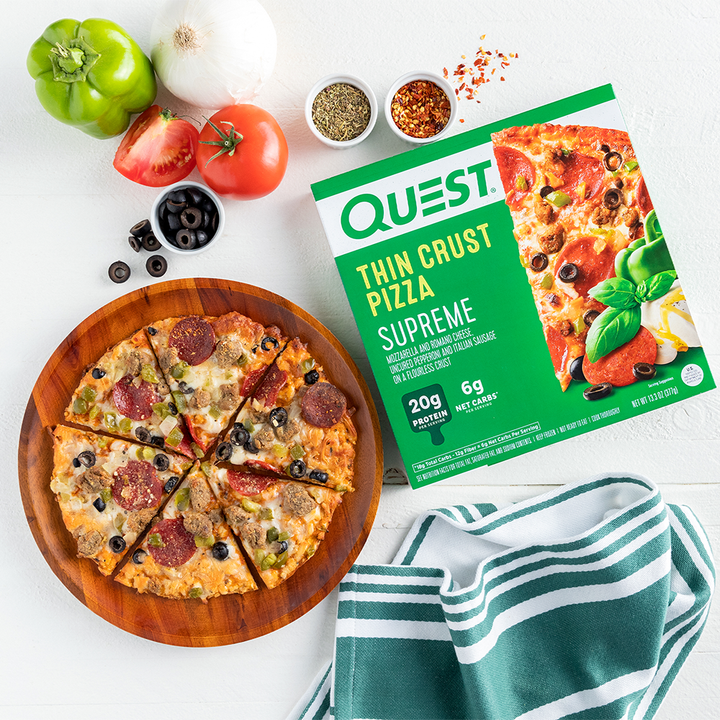 Quest Supreme Thin Crust Pizza Package staged with pizza on cutting board with toppings and towel.