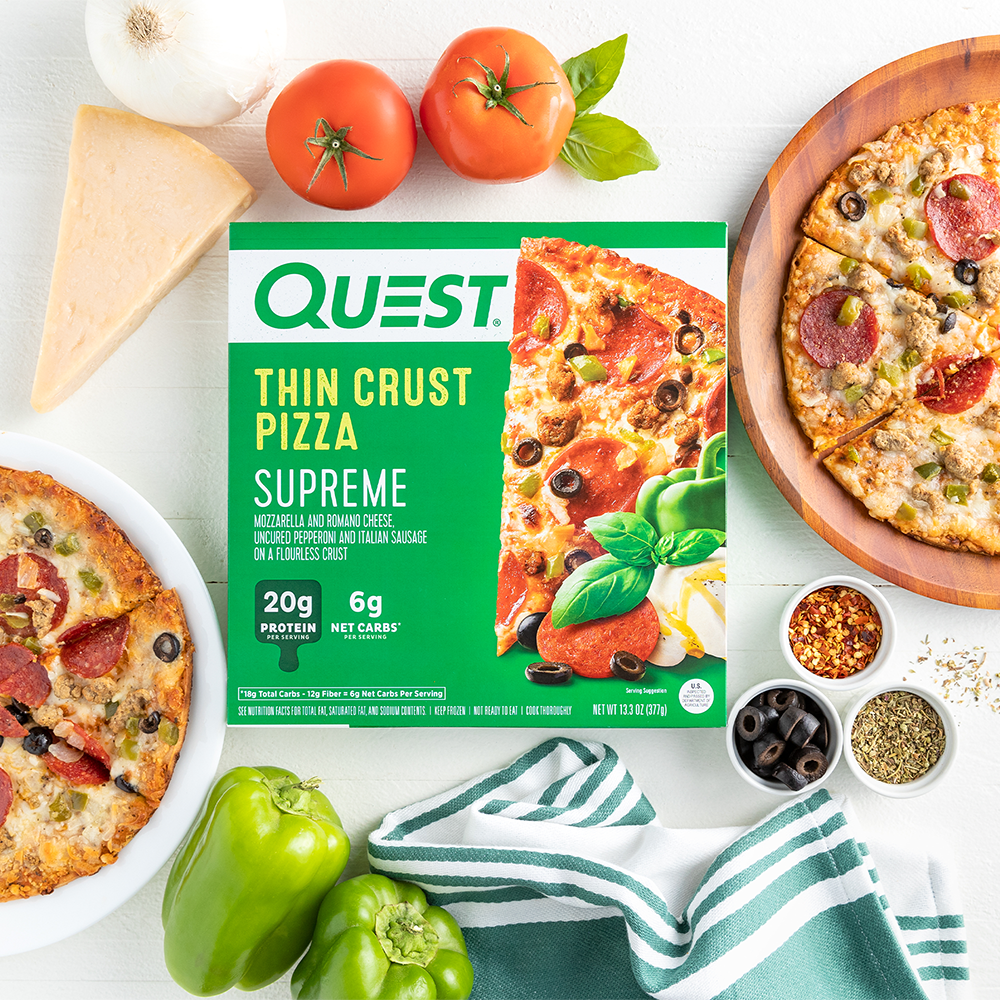 Quest Supreme Thin Crust Pizza Package staged with pizza on cutting board with toppings and a towel.